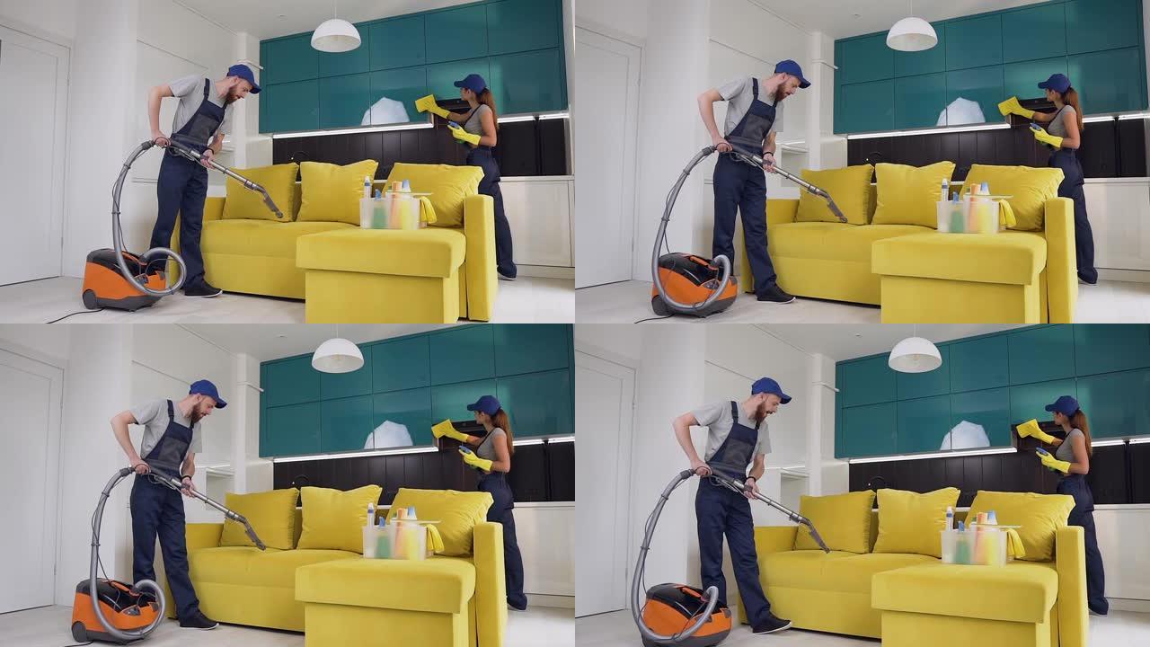 清洁服务工人的迷人照片，男人用吸尘器打扫沙发，女人擦家具