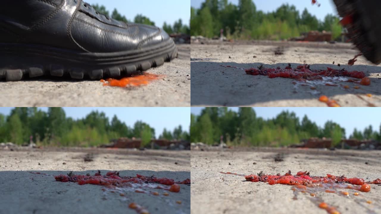 一个巨大的脏靴子压碎了一个小番茄。宏观。他走进来，用脚压碎了一个西红柿。慢动作