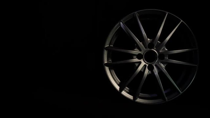 汽车用新型合金车轮在黑暗背景下滚入车架。汽车和车辆用现代金属设备。奢华设计。昂贵的碳光亮钢盘。清洁铝