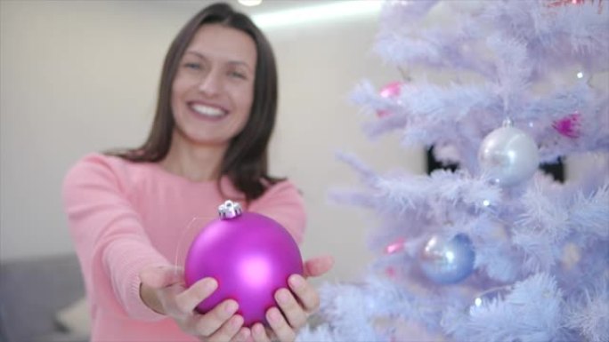 微笑的年轻女士用粉红色的小毛球将双手伸向相机，为每个人准备了她最喜欢的玩具。