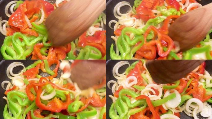 红辣椒和青椒配洋葱在锅里炒，拌上木铲。