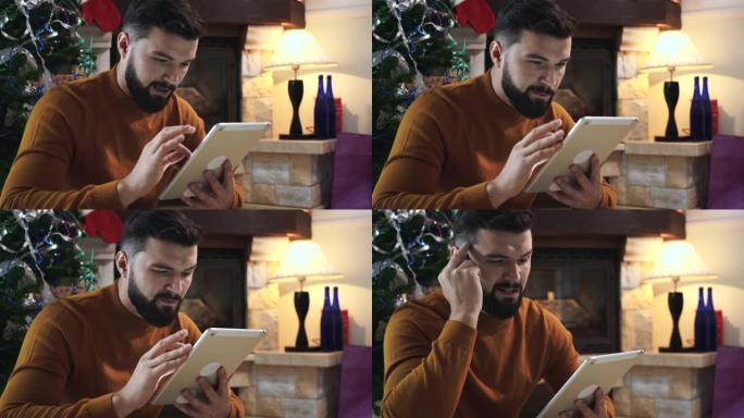 集中高加索人的肖像，黑胡子坐在圣诞树前，使用平板电脑。严肃的年轻人在除夕夜网上搜索礼物。假期，惊喜，