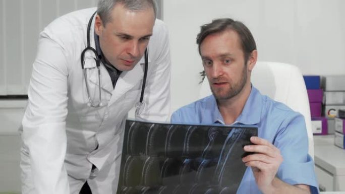成熟的男性外科医生向他的同事咨询患者的MRI扫描