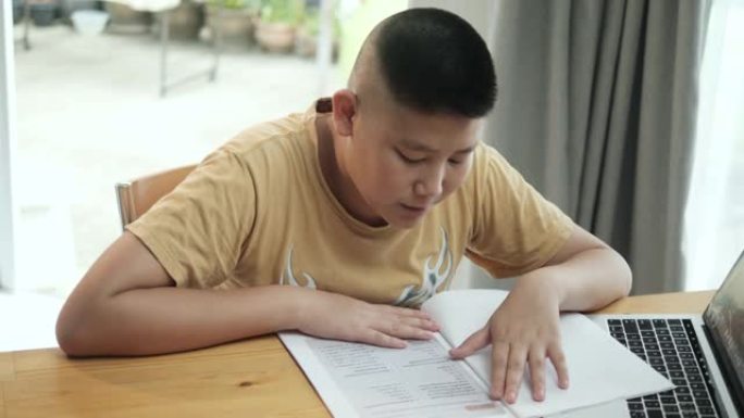 亚洲男孩阅读新型冠状病毒肺炎在家上学的工作单。