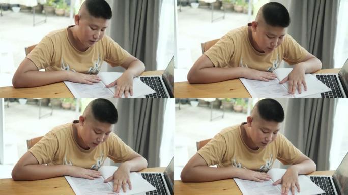亚洲男孩阅读新型冠状病毒肺炎在家上学的工作单。