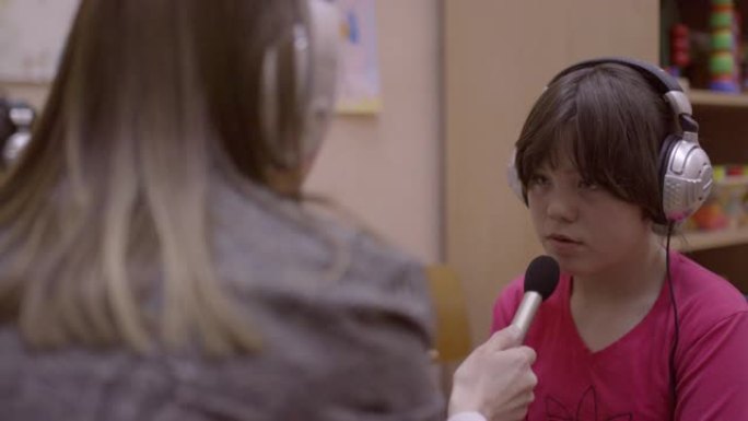 言语治疗师后戴着耳机重复的残疾女孩