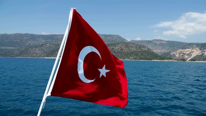 在阳光明媚的日子里，土耳其国旗在风中挥舞着地中海。