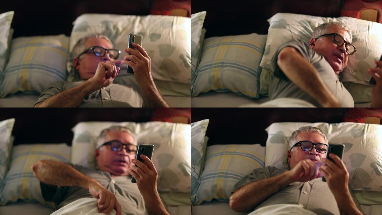 年长的男人晚上在床上看手机屏幕