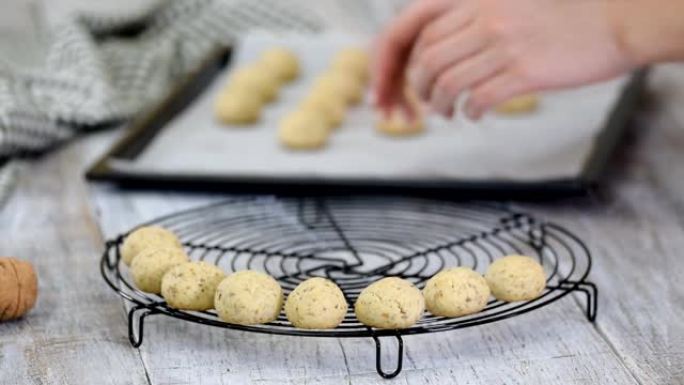 女人在家做雪球饼干。女人的手把饼干放在铁丝架上冷却。