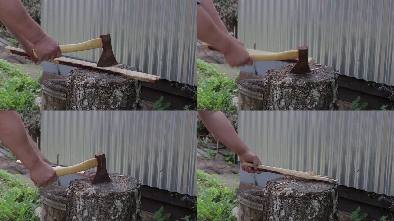 男性的手用斧头在树桩上砍一根棍子。