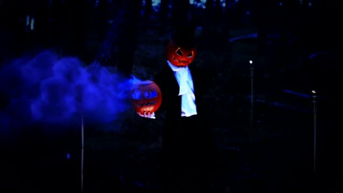 幽灵般的南瓜头男人在森林里拿着一个蓝色烟雾的大南瓜