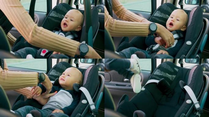 特写男婴，坐在车内的婴儿汽车座椅上。门打开，母亲的手解开安全带，并小心地将婴儿带出汽车。慢动作