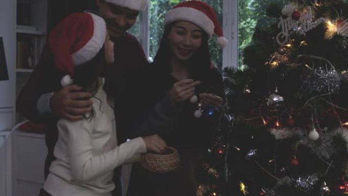 年轻的家庭父亲，母亲和女孩装饰圣诞树，为即将到来的圣诞节做准备