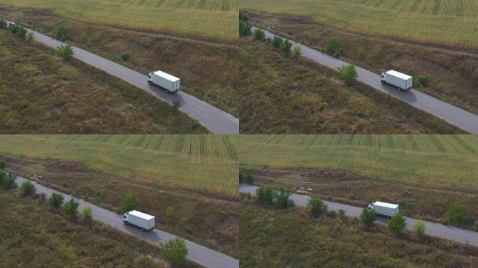 载货拖车在公路上行驶并运输货物的卡车的航拍。飞越送货卡车，沿着高速公路经过农村的田野。风景优美的自然