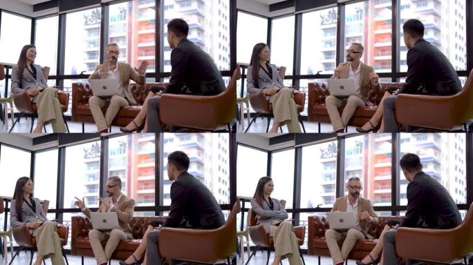 商务高级老板和年轻人团队合作合作伙伴会议并坐在带有外部摩天大楼背景的沙发椅上