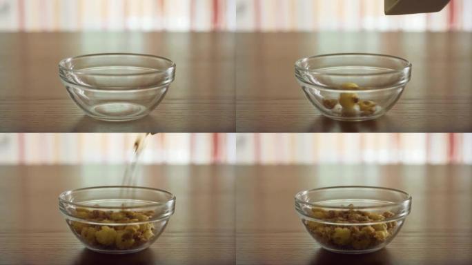 将脆饼和玉米片放入透明的玻璃碗中，以便早晨在家在阳光下的木制桌子上做饭。