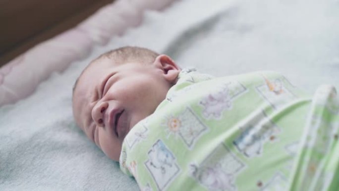新生婴儿躺在闭着眼睛的薄纱襁褓中