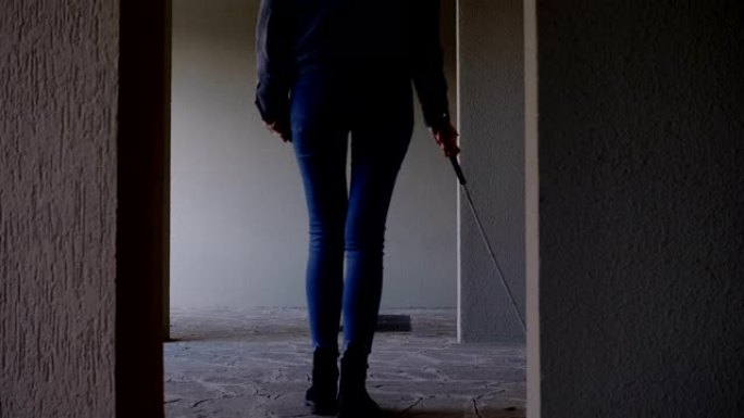 盲人妇女在空荡荡的公寓里用棍子走路。失明，自治，定向