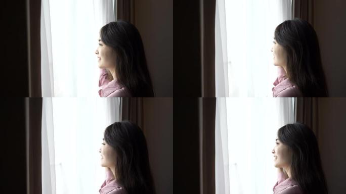 亚洲年轻女子清晨透过窗户看风景的慢动作场景 (4K)