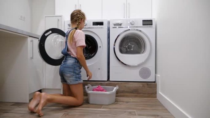 十几岁的女儿在洗衣店做家务，把脏衣服放在洗衣机里。女孩帮助她的母亲。慢动作