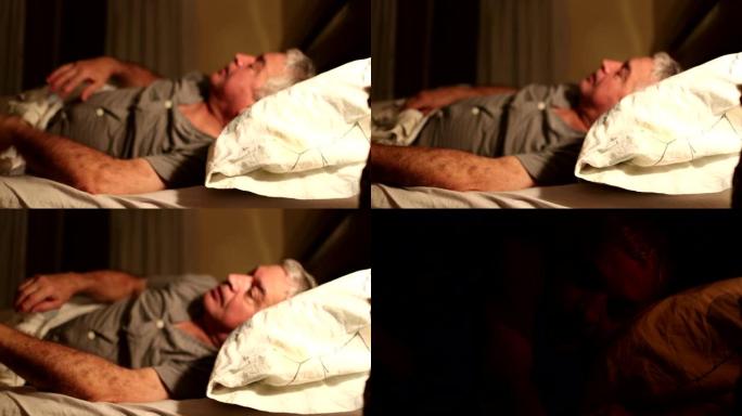晚上躺在床上的老人关掉床头灯，人要睡觉