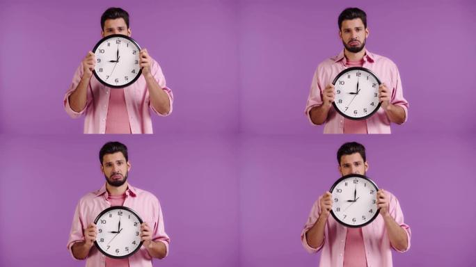 悲伤的男人用紫色的时钟遮住脸