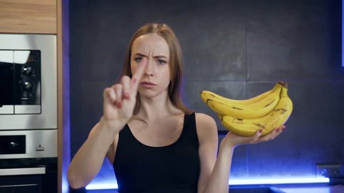 一只手拿着香蕉并表现出不喜欢的迹象的迷人苗条年轻女子的前视图