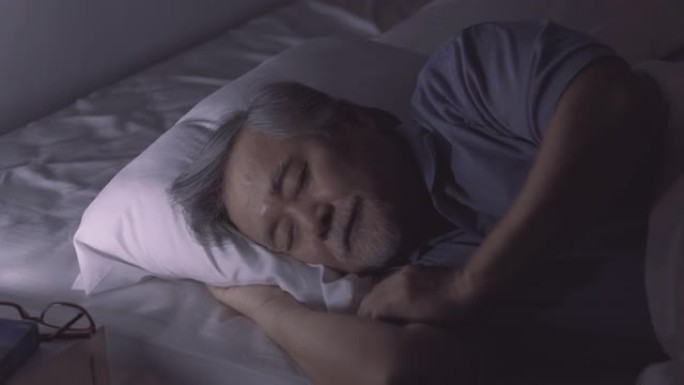 老年男子睡在床上做梦，然后老年女子亲吻并在卧室睡觉时关灯