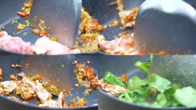 女人的手在煎锅中与辣椒粉，蚝油，厨房里用煤气在热火上放糖，用猪肉片炒芥蓝。美味的泰国菜。