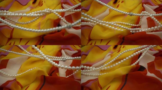 珍珠珠宝在时尚的多色柔软织物上的飞行和波浪运动，慢动作。