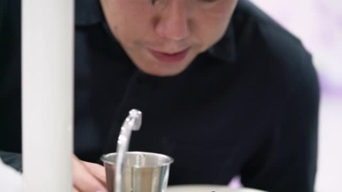 亚洲男子完成牙科护理后在牙科诊所用水漱口
