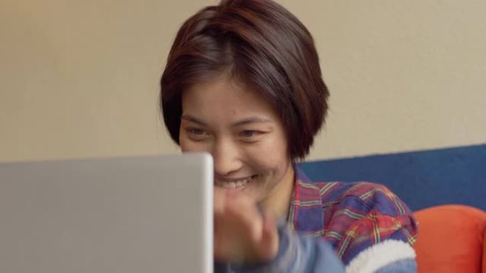倾斜特写镜头真实的亚洲年轻女子短发鼻中隔在笔记本电脑上工作，大笑，关闭电脑，面带微笑地看着相机
