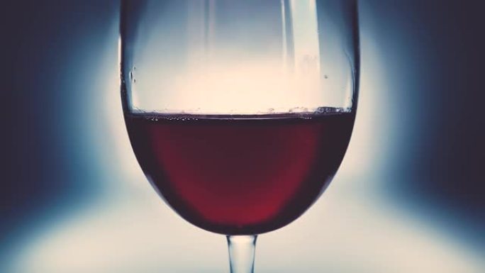 创意微距慢动作视频红酒在一杯和一滴落的葡萄酒。一杯酒慢慢落下的酒特写。旧复古垃圾复古风格，柔和褪色。