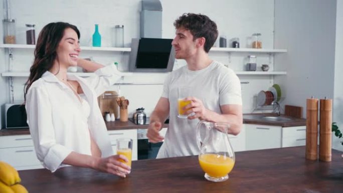 男人在厨房喝橙汁时拥抱性感女友