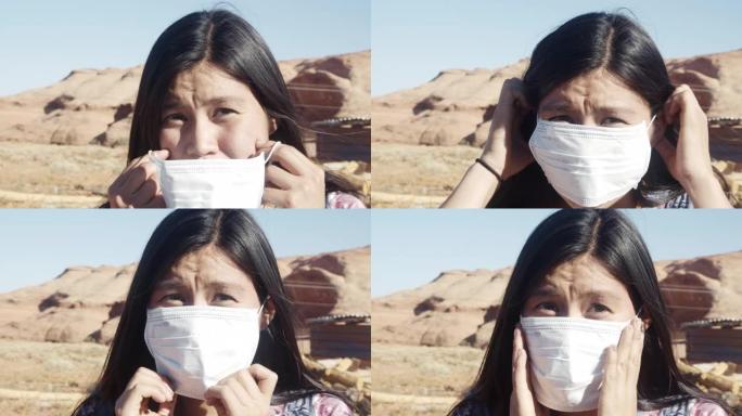 亚利桑那州北部沙漠中漂亮的十几岁的纳瓦霍印第安人女孩在肖像中透过新型冠状病毒肺炎面具微笑，背景是纪念