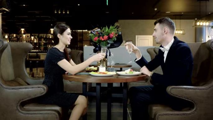 年轻夫妇在现代餐厅约会时聊天和喝白葡萄酒。4K