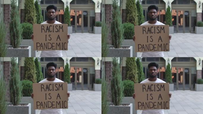 一名年轻的非洲裔美国人站在纸板海报上，种族主义是公共户外场所的一种流行病。街头示威。慢动作。特写