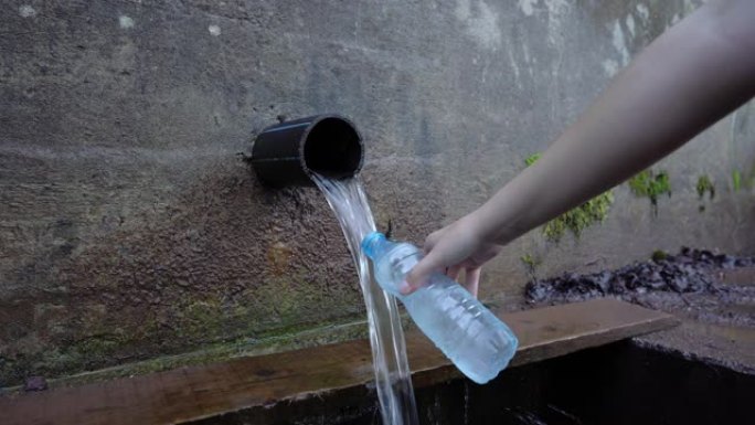 夏季，未知的白人妇女从塑料瓶中的山泉取水的近景-自然和新鲜的概念