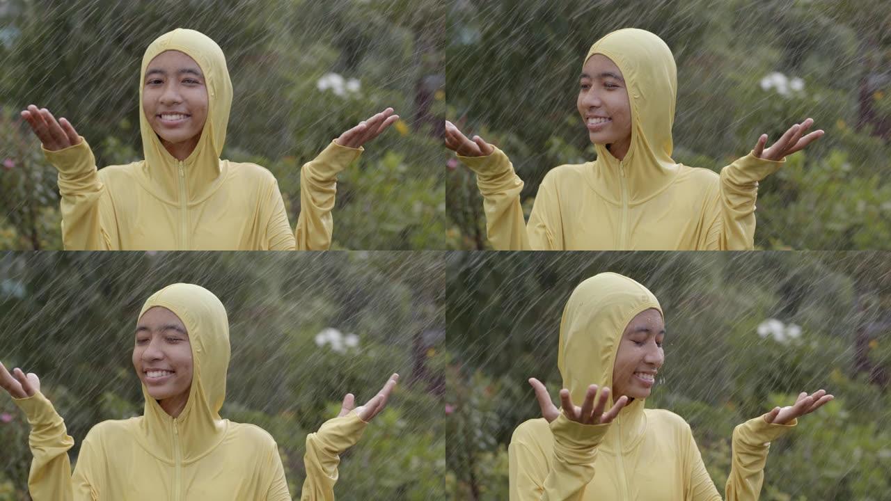 快乐的亚洲女孩在雨中玩耍，在大自然中享受乐趣。慢动作
