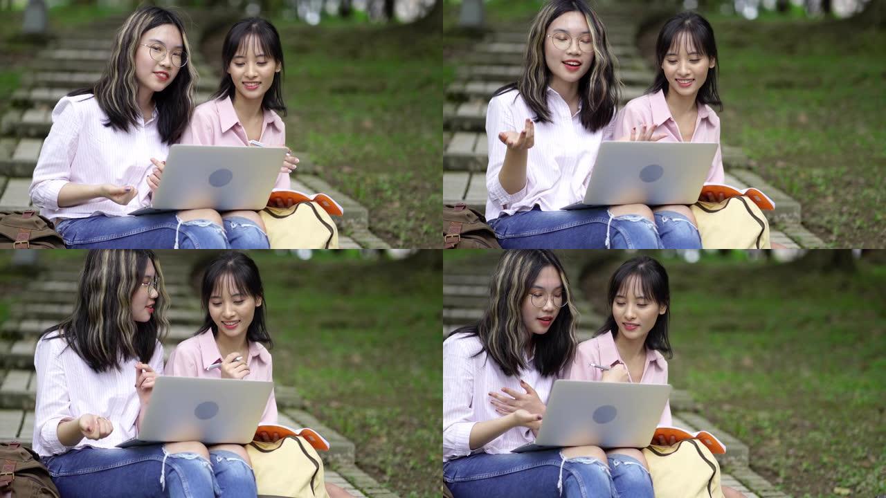 两名年轻的亚洲女学生在公园使用笔记本电脑