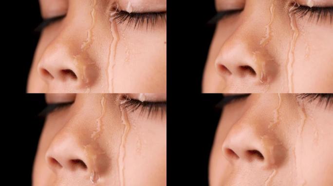 水滴流淌在小女孩的脸上。一个在黑色背景上哭泣的小女孩。特写