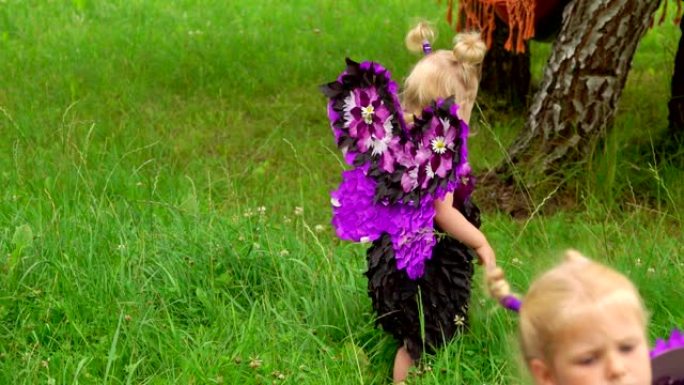 穿着蝴蝶服装的女孩在草坪上行走