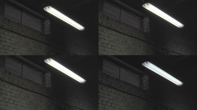 荧光灯在工厂，机库，车间部门的暗室中打开和关闭。砖墙和窗户的工业制造区停电，电气短路