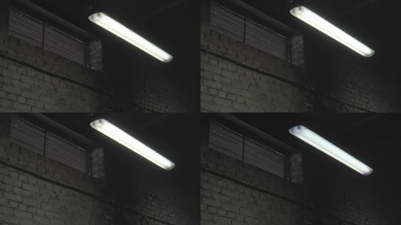 荧光灯在工厂，机库，车间部门的暗室中打开和关闭。砖墙和窗户的工业制造区停电，电气短路