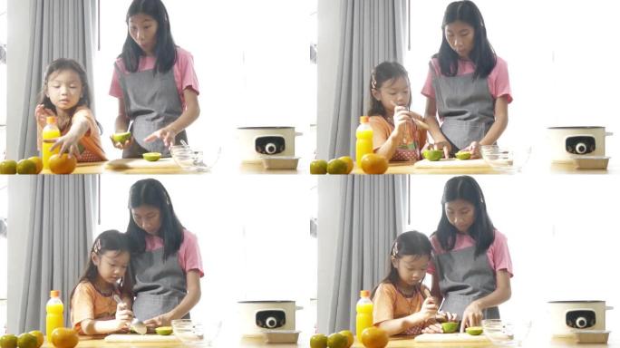 亚洲女孩教她的妹妹如何挤橙汁在家里加工甜果冻。