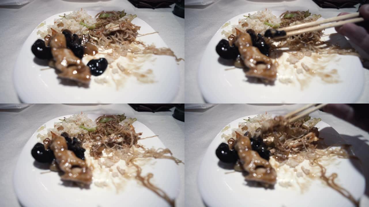 在一家亚洲餐厅吃牛肉面，米饭和黑蘑菇作为晚餐，用棍子吃热的传统中国菜