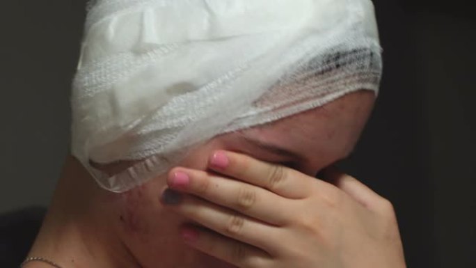 头部受伤的悲伤女人的肖像坐在床上，头部被绷带包扎