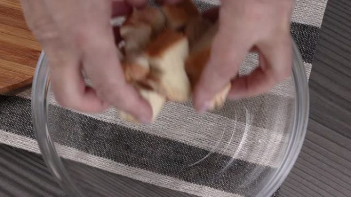 女人的手将面包块放入玻璃碗中，俯视图