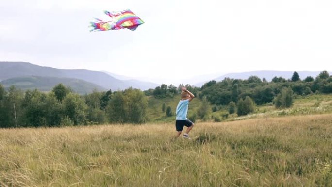 男孩奔跑并在山中发射一条蛇风筝