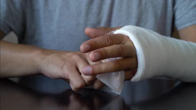 男子用石膏包裹的断手擦拭手指